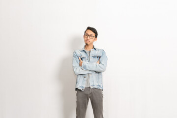 A guy wearing a denim jacket with arms crossed looking sideways. Indonesian or southeast asian isolated model in front of white background.