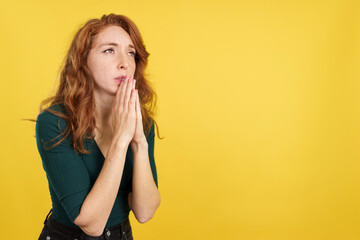 Redheaded woman looking up while praying with folded hands