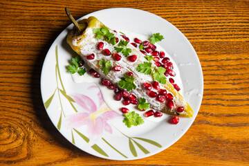 Pomegranate and Chiles en nogada dish on wooden background...
