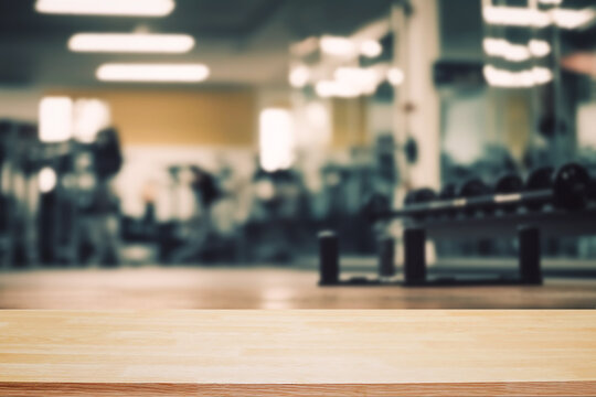 Blurred background of fitness gym and wooden table free space for product display