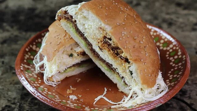 Mexican cemita sandwich with oaxaca cheese. split in half turning on plate