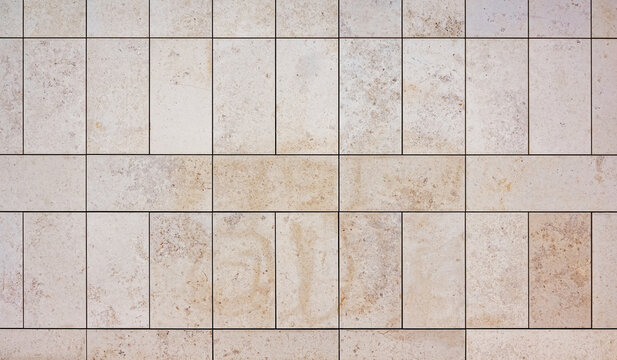 texture of a tiled beige stone wall as background, natural stone wall texture as background. Close-up of a wall clad in limestone