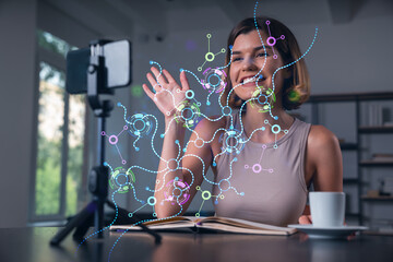 Happy woman is making video blog using smartphone on a tripod explaining with hands at office workplace. Concept of online stream, business education, conference call. Ai technolgy hologram