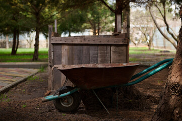 Still life with wheelbarrow standing near a compost pit in a garden plot. Agriculture. Eco farming. Gardening. Agricultural hobby. Sustainable resources. Sustainability. Zero waste concept. Composting