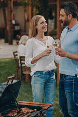 Happy young couple toasting with wine while having picnic with their family outdoors
