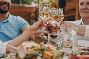 Close-up of multi-generation family toasting with wine while enjoying dinner outdoors together