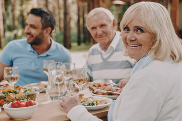 Happy multi-generation family enjoying dinner while sitting outdoors together