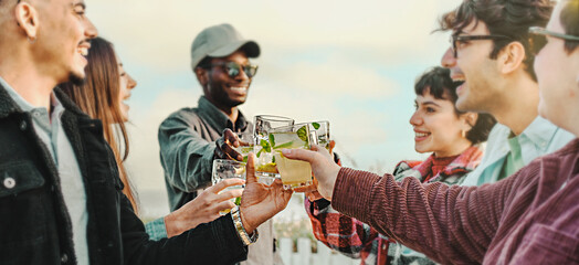 Multicultural Friends Toasting with Mojitos - Panoramic shot of young friends in a circle, smiling,...