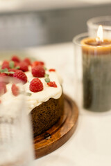 A sweet cake with white frosting an a lot of red raspberries and green garnish on top