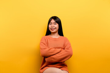 Fototapeta premium asian girl Pretty wearing an orange casual dress. yellow background Celebrate the victory with a happy smile and the winner's expression with a raised hand. happy expression