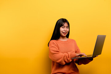 Naklejka premium Asian woman and laptop and are happy to work Photo of a beautiful Asian woman who is happy working at home. using a laptop computer yellow studio work at home concept