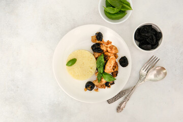 Couscous with chicken meat and prunes with walnuts on a gray background.