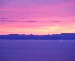 Obraz premium 夕焼けの海に浮かぶ漁火と佐渡島