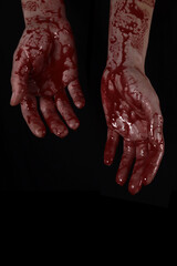 Raised bloody creepy hands on a black background, the concept of murder, nightmares, Halloween. Vertical Orientation