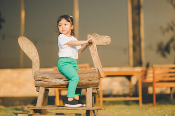 baby girl play on a wooden rocking horse on the outdoor play ground with happy time on evening time