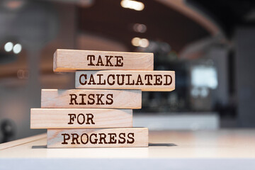 Wooden blocks with words 'Take calculated risks for progress'. Business concept