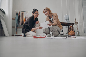 Two attractive female fashion designers planning new collection in workshop together