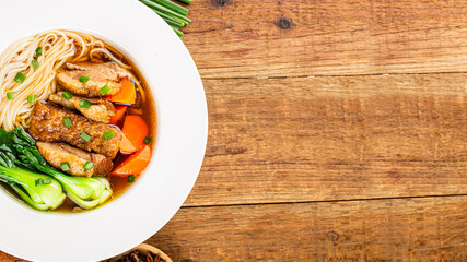 Spicy red soup beef noodle in a bowl on wooden table