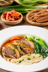 Spicy red soup beef noodle in a bowl on wooden table