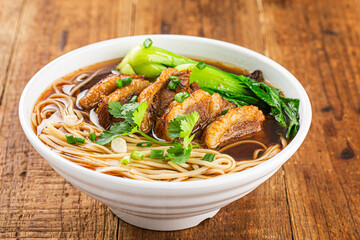 Spicy red soup beef noodle in a bowl on wooden table