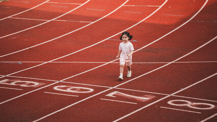 Baby asian girl run jogging at running track, running field at stadium. little girl running at...