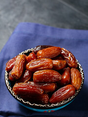 Bowl of pitted dates on a blue linen napkin. Tasty sweet dried dates in bowl. Ramadan food