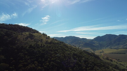 Fototapeta na wymiar Foto de paisagem com colinas montanhas céu azul e floresta com drone