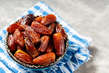 Pitted dates in bowl on a linen napkin. Close up of bowl with healthy snack - dried sweet dates. Healthy organic vegetarian food