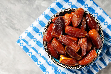 Pitted dates in bowl on a linen napkin. Close up of bowl with healthy snack - dried sweet dates. Healthy organic vegetarian food