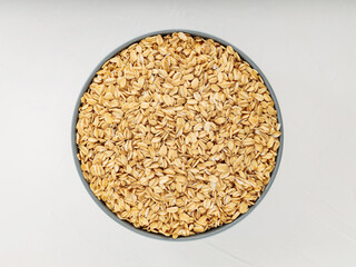 Oat flakes bowl on a white background. Raw oatmeal for a healthy breakfast. Copy space. Top view