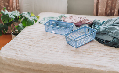 Different clothes with blue containers on a made bed.