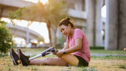 Athlete with prosthetic leg doing warm up exercise on park. Woman wearing prosthetic equipment  for jocgging.