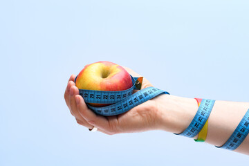 Jabłko trzymane w dłoni owinięte centymetrem krawieckim