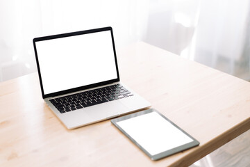 Fototapeta premium Laptop and tablet with blank screens for text or advertising on wooden table.