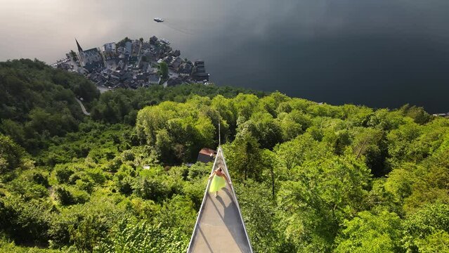 Woman is walking in skywalk of Hallstatt platform, aerial shoot of nature lake and park