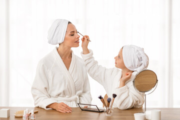 Beautiful Young Mom And Little Daughter In Bathrobes Doing Makeup At Home
