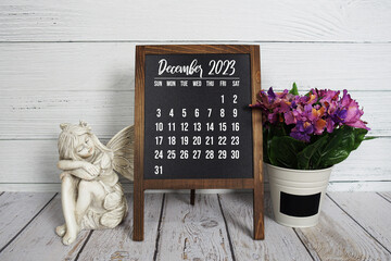 December 2023 monthly calendar on easel stand on wooden background