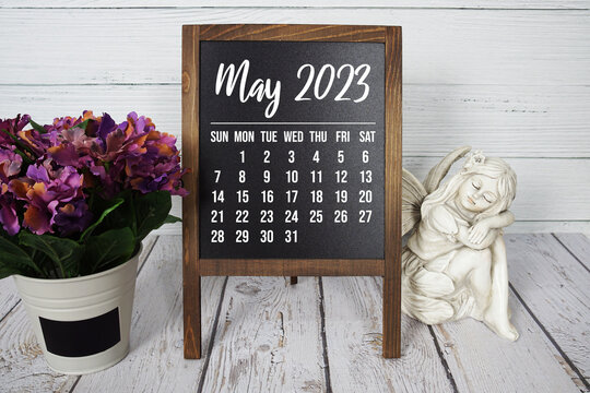 May 2023 monthly calendar on easel stand on wooden background