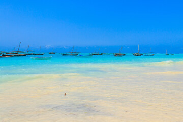 View of tropical sandy Nungwi beach and traditional wooden dhow boats in the Indian ocean on Zanzibar, Tanzania