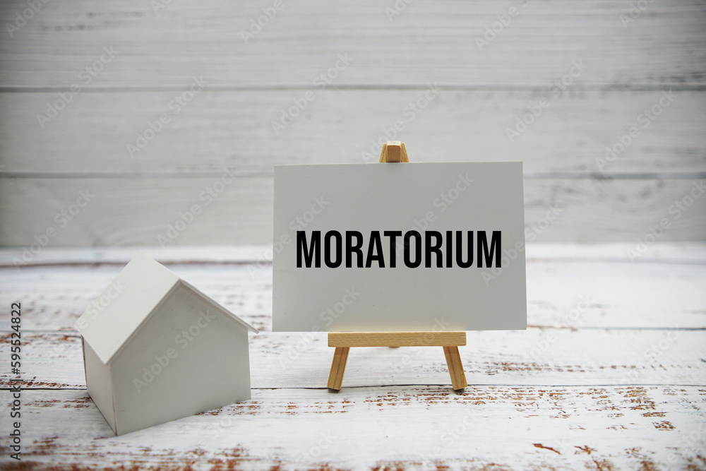Poster moratorium text message with calculator and house model on wooden background