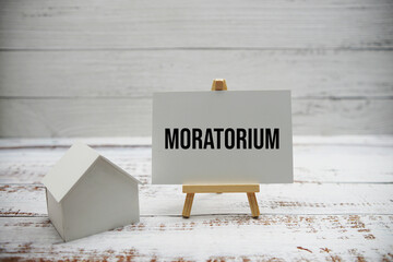 Moratorium text message with calculator and house model on wooden background
