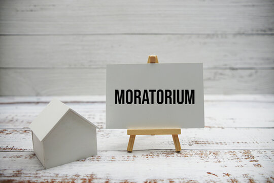 Moratorium text message with calculator and house model on wooden background