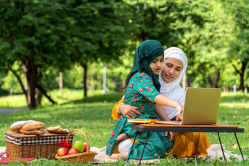 Muslim mother and asian muslim kid girl learn and look at laptop computer reviewing lesson study with online education e-learning.student look for educational knowledge in homeschool at home.Education