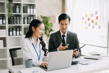 Two business workers talking on the smartphone and using laptop at the office.