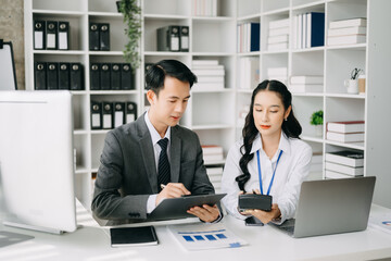 Two business workers talking on the smartphone and using laptop at the office.