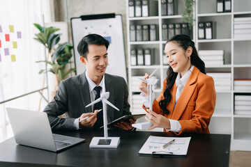 Alternative energy engineer pointing to a solar power panel and discuss with  business colleague team for the future power in the office.
