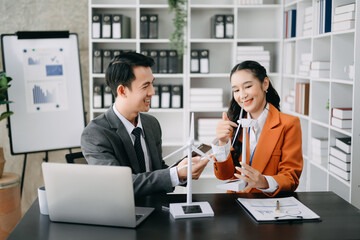 Alternative energy engineer pointing to a solar power panel and discuss with  business colleague team for the future power in the office.