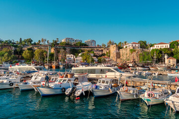 Fototapeta na wymiar View of a cozy little historical port with turquoise water and boats in the city of Antalya.