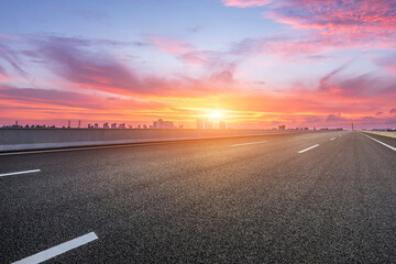 Asphalt road and skyline with sky clouds at sunrise
