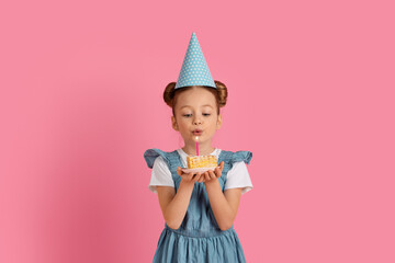 Cute Little Girl Wearing Party Hat Blowing Candle On Birthday Cake